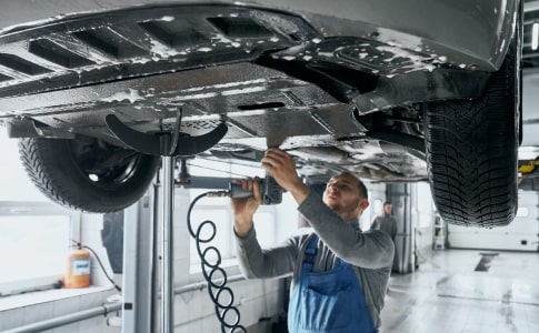 Technician using paintless dent repair (PDR) tools on a car door panel