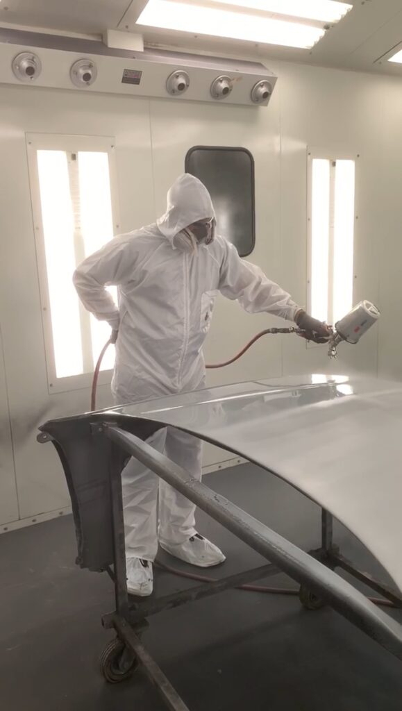 Auto Body Shop Philadelphia paint technician applying Sherwin-Williams finish to vehicle panel in spray booth