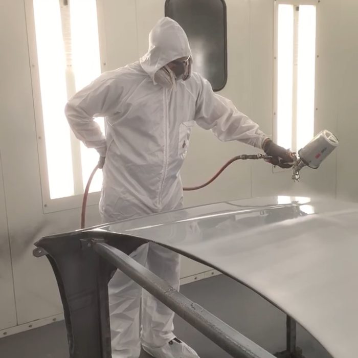 Auto Body Shop Philadelphia paint technician applying Sherwin-Williams finish to vehicle panel in spray booth